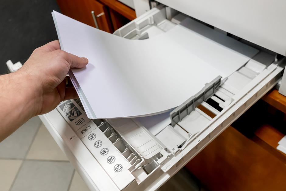 Hand sets the paper stack in the laser printer.