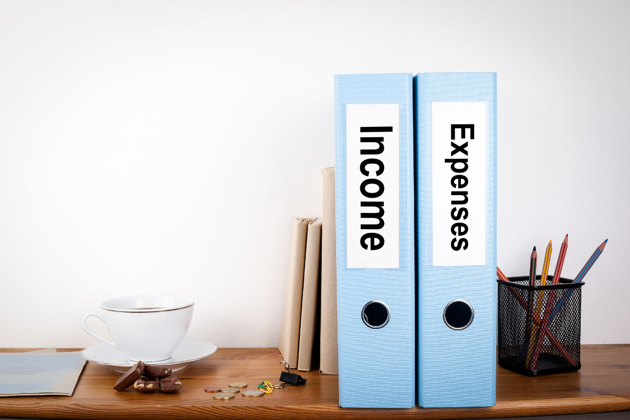 Income and Expenses binders stationery on a wooden shelf.