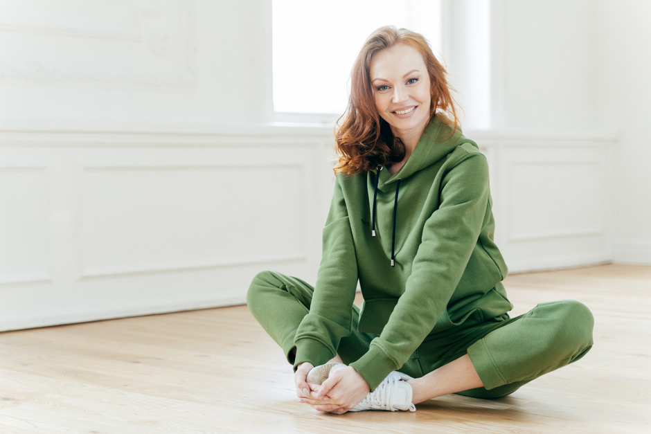 Indoor shot of a woman in green sweatsuit resting after cardio exercise.