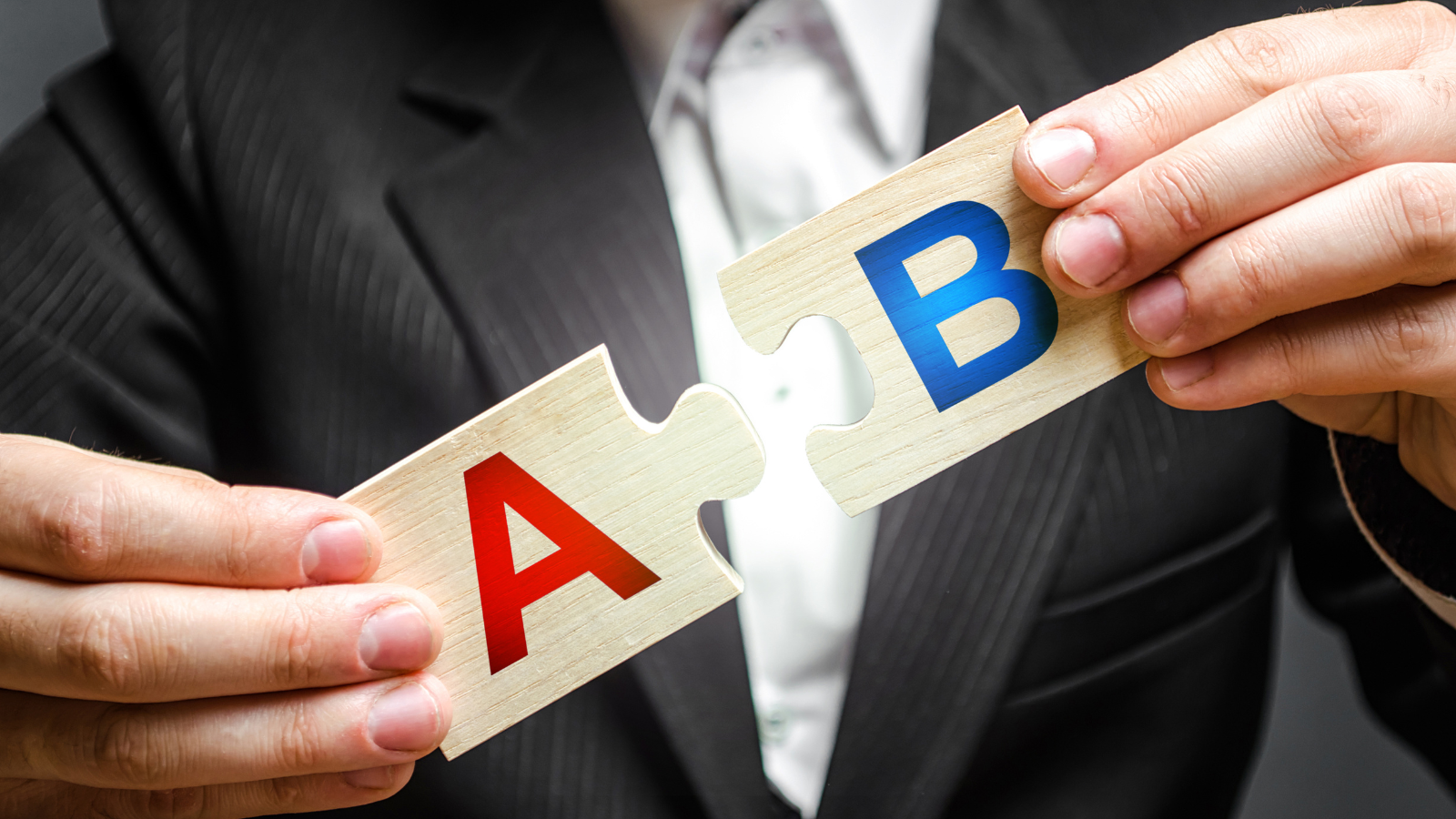 Male businessman holding A and B puzzle.