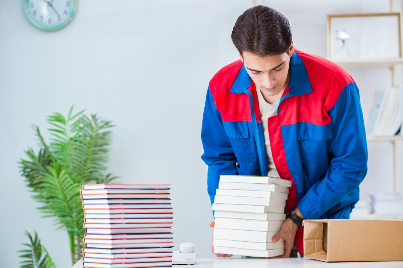 Male worker stacking printed coloring books in a publishing house.