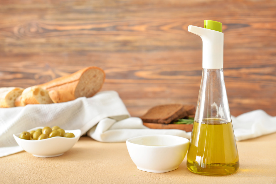 Olive oils, bread and oil dispenser on table.