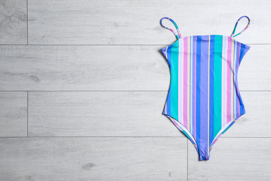 Top view: one-piece swimsuit on wooden background