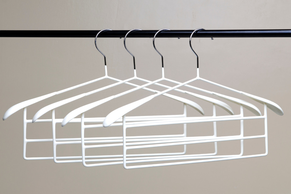 Set of four white non-slip hangers arranged on a clothes rack.