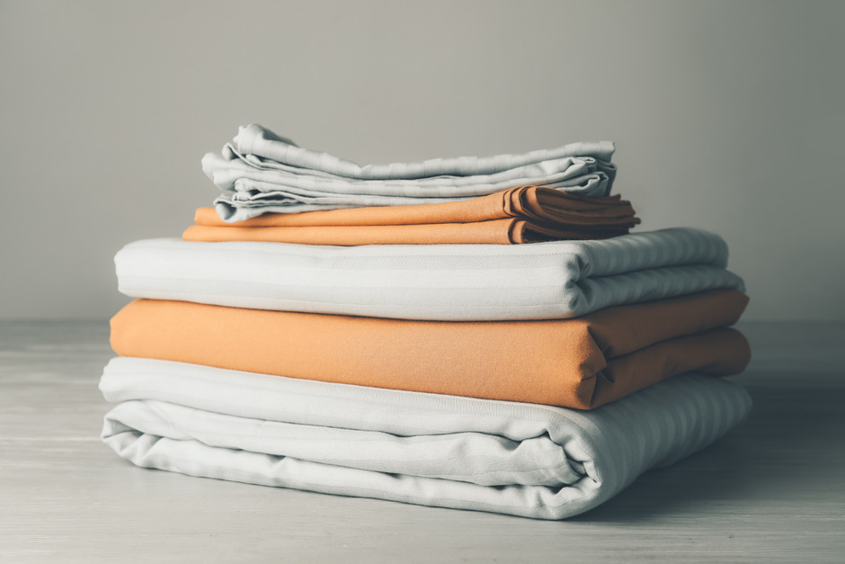 Stack of clean bed sheets on table.
