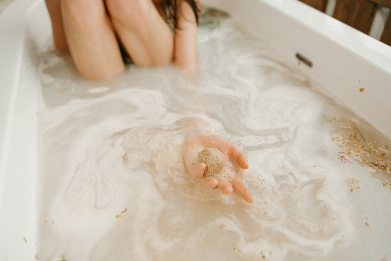 Woman in bathtub holding hypoallergenic bathbomb.