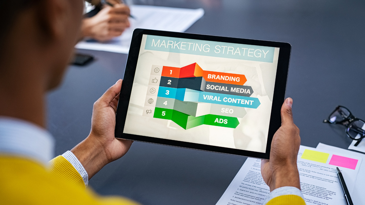 A man holding a tablet displaying his marketing strategy infographic.