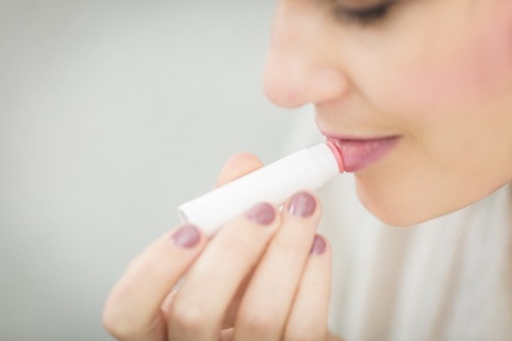 A woman applying lipstick.