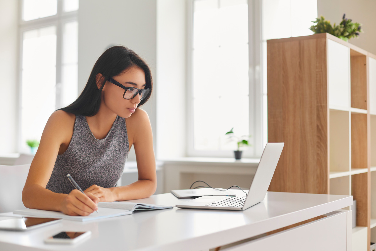 An aspiring hair beauty provider eagerly researches niche options on her laptop, taking detailed notes.