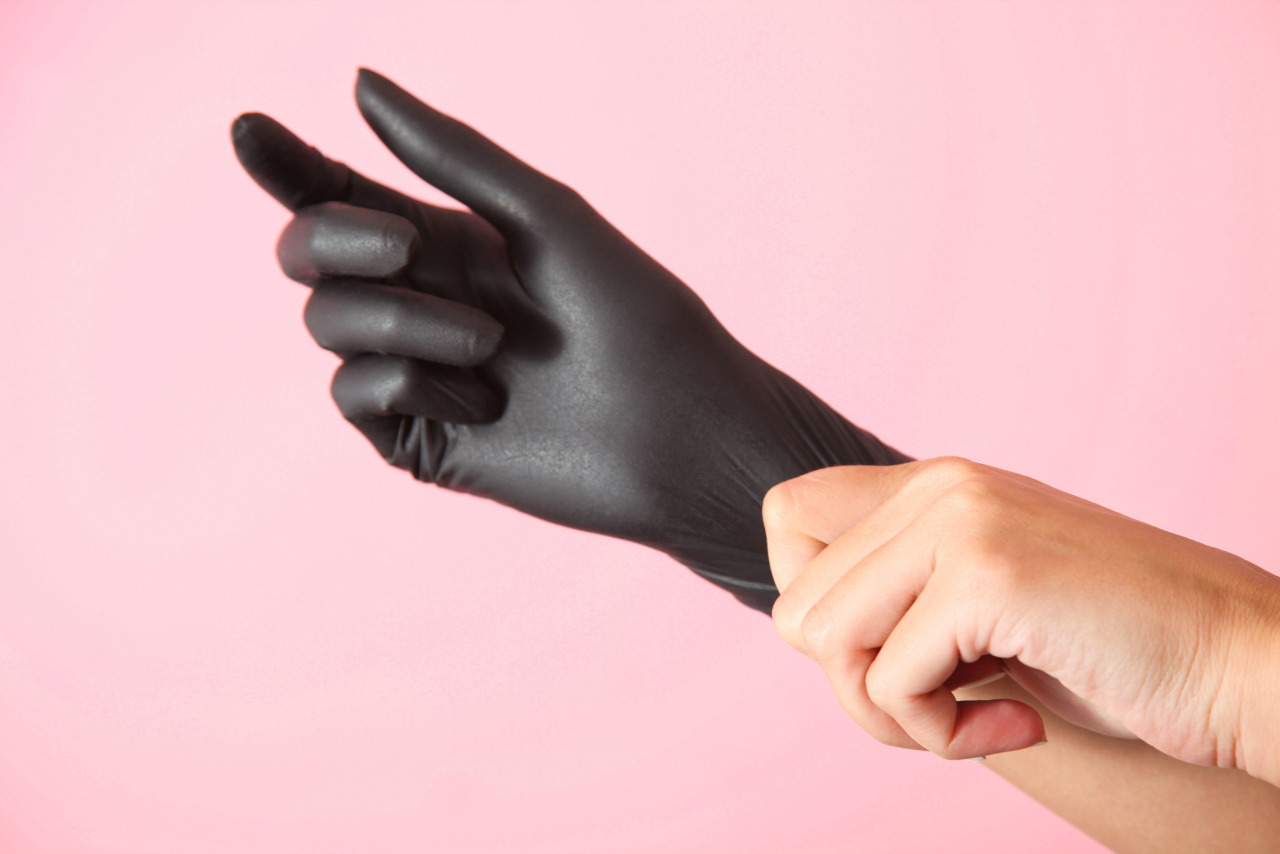 Person's Hand Wearing Black Glove on Pink Background.