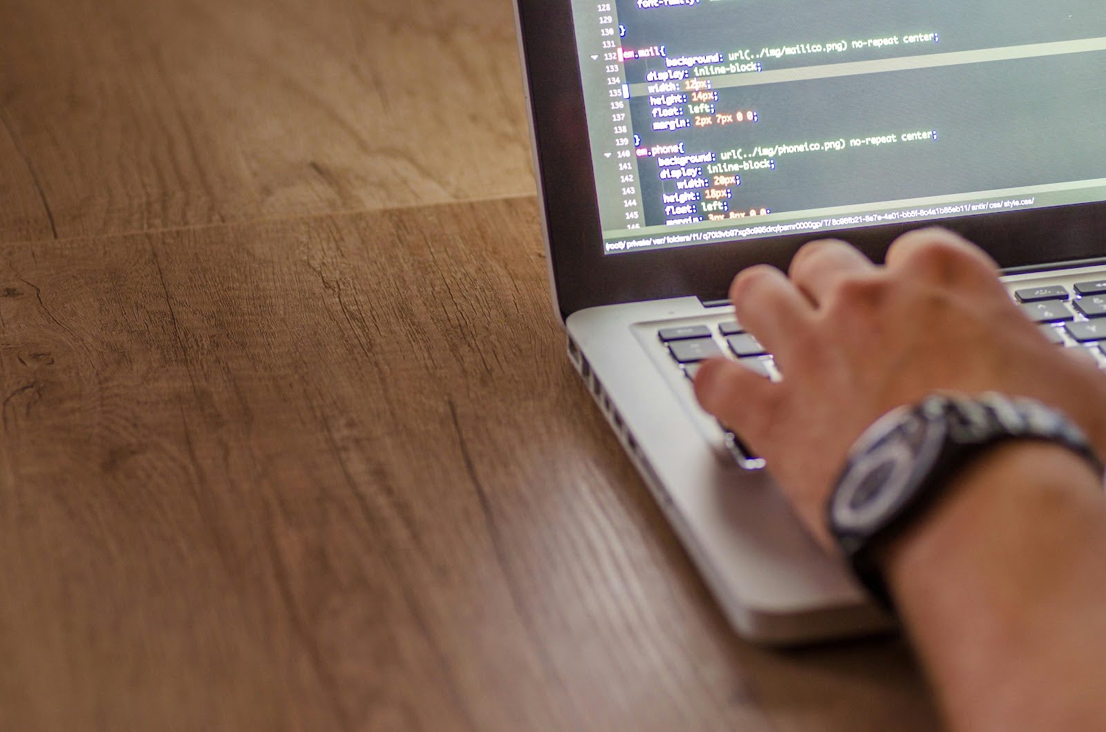 Hand writing code on a laptop, representing cloud security and AWS development work
