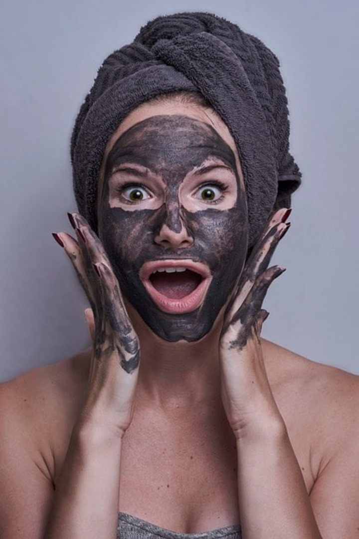 A woman with a charcoal face mask.