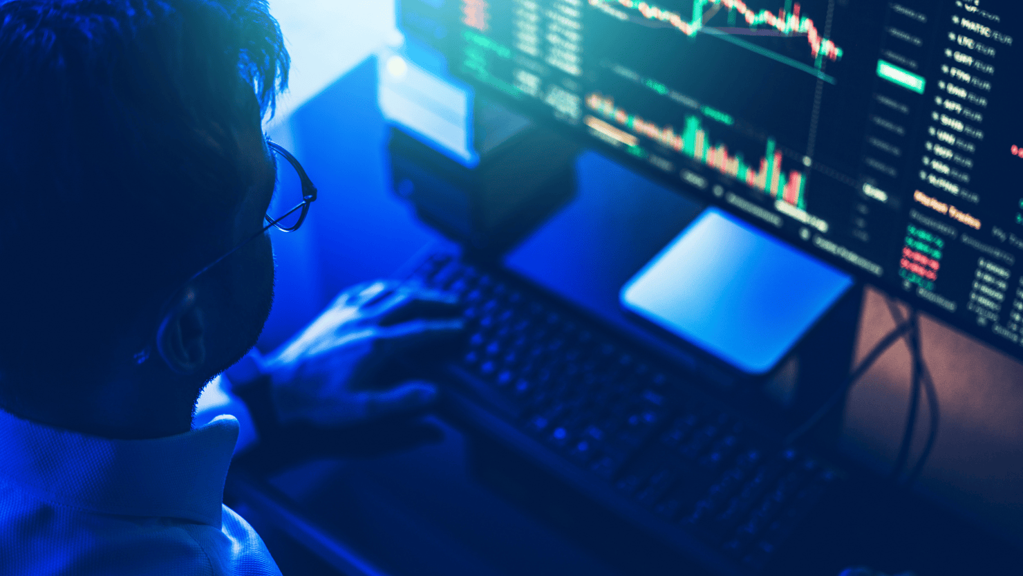 Person analyzing cryptocurrency or stock market data on a multi-screen computer setup