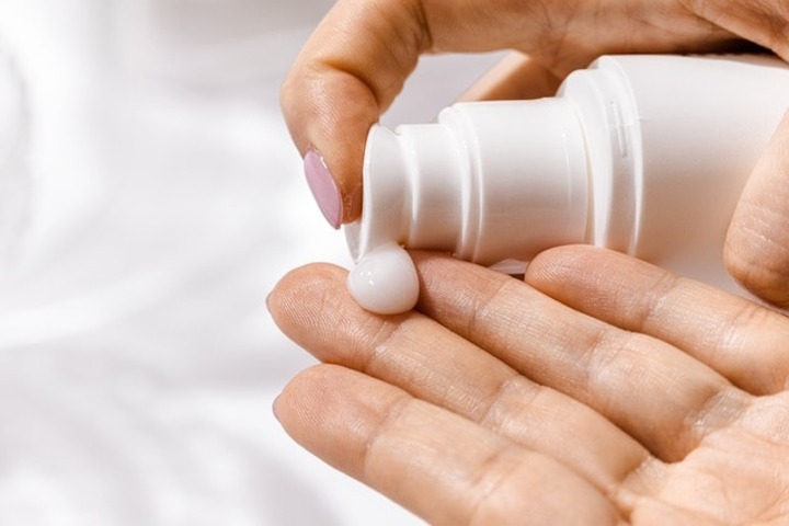 A person applying hand moisturizer.