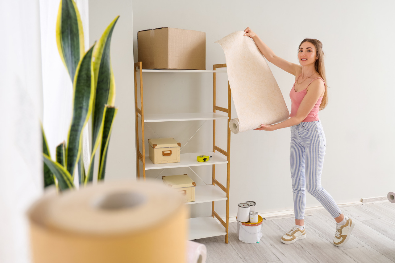 A woman unrolls peach-colored wallpaper.