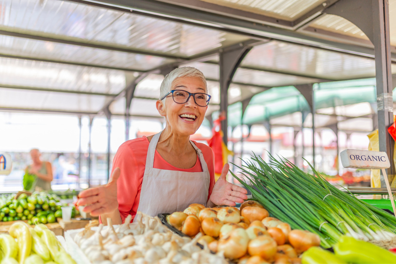 Old lady selling fresh vegetables at farmer's market.