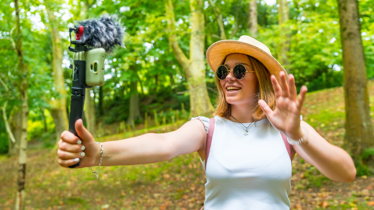 Young woman hiker recording vlog to promote travel agency.