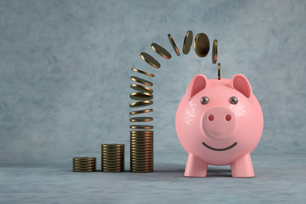 Savings piggy bank with stacks of golden coins on the side.