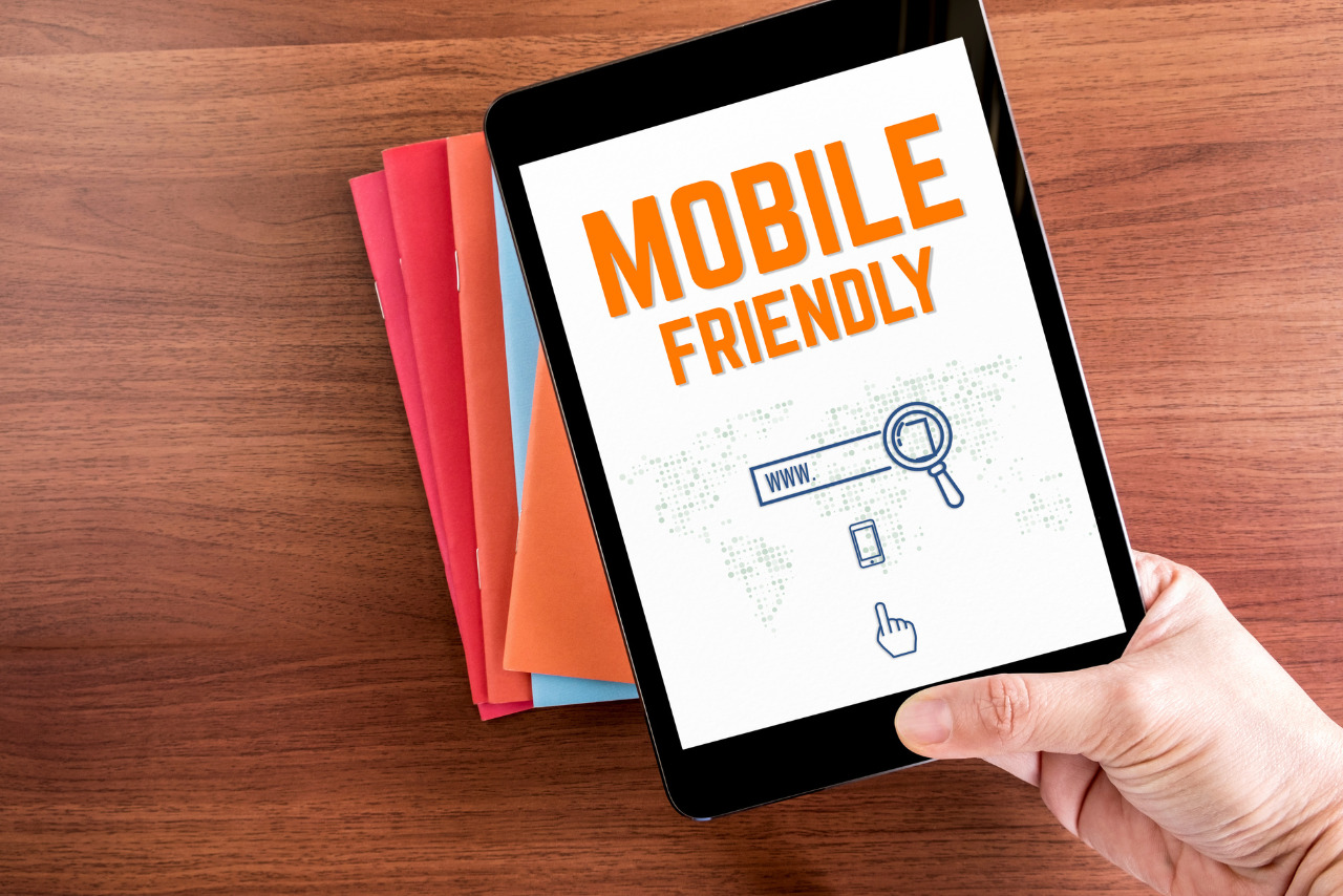 Top view of hand holding tablet with mobile friendly word.