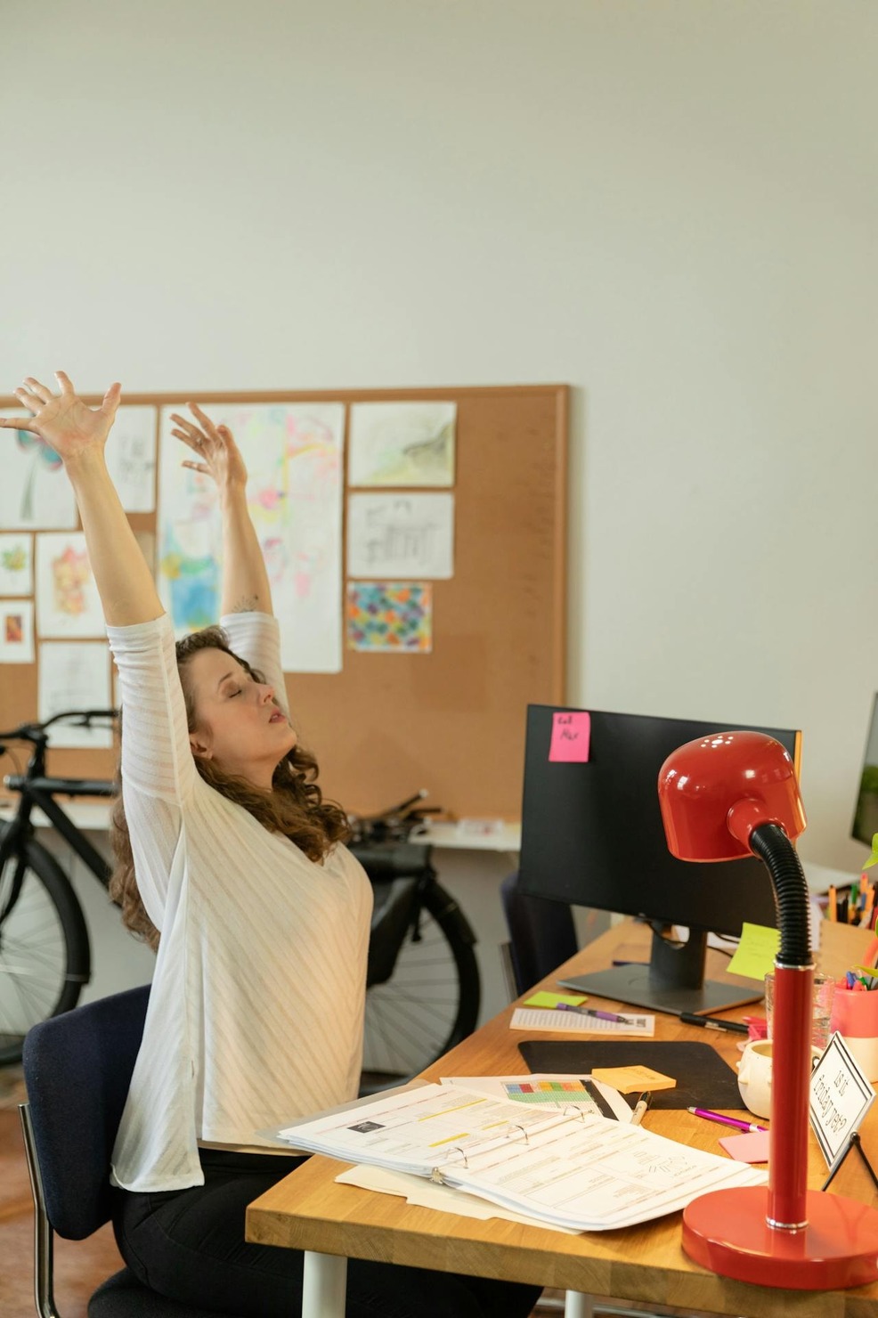 A woman stretching her body while sitting at her desk