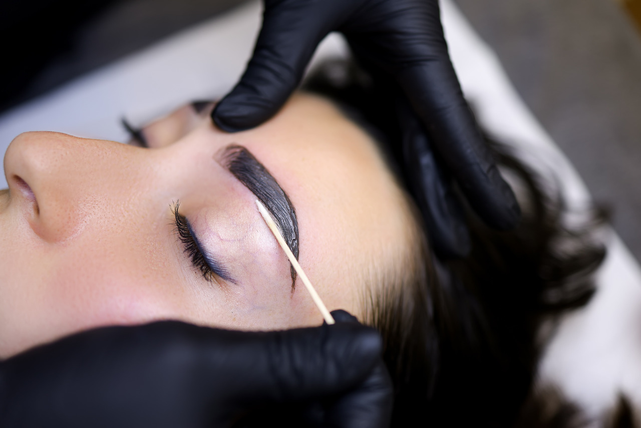 A close-up of the process of coloring eyebrows with dye, highlighting a popular beauty trend.