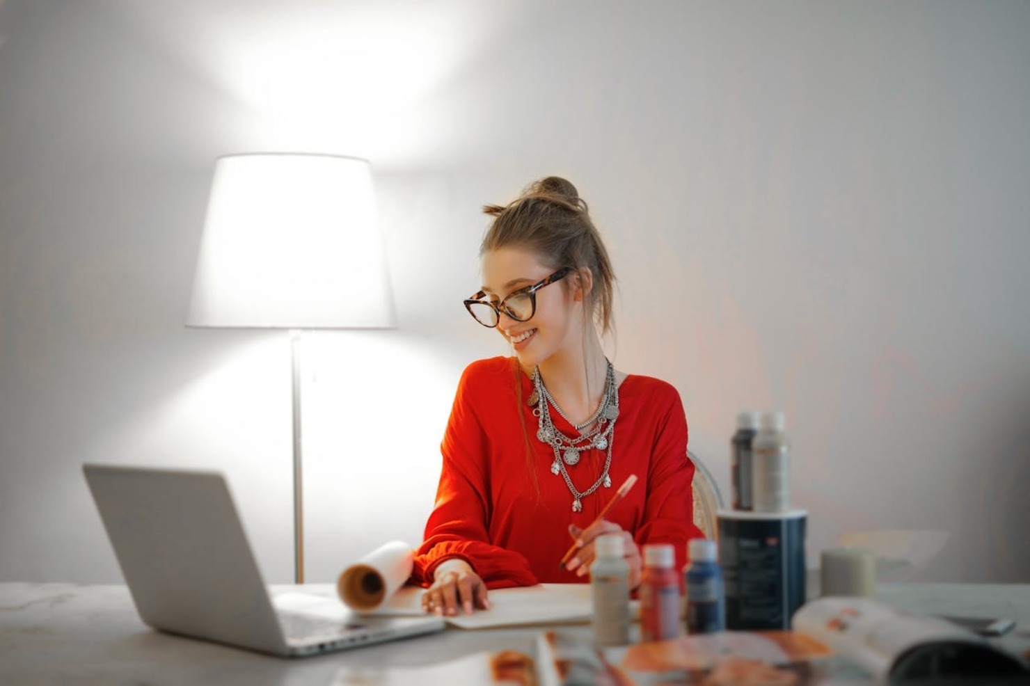 A woman at her workstation smiling and taking down notes