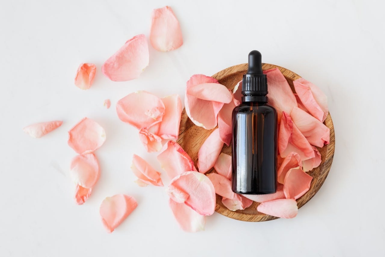 A photo of a cosmetic product and flower petals on white surface