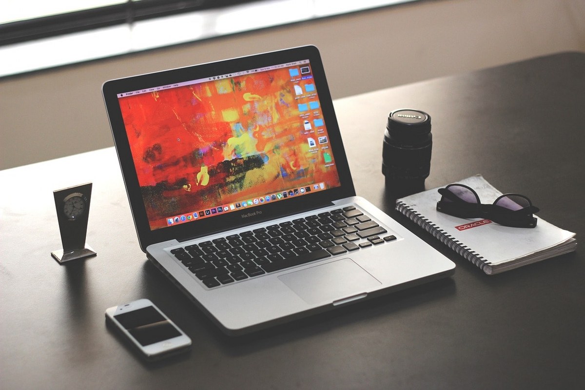 A laptop, a phone and a notebook on a table.