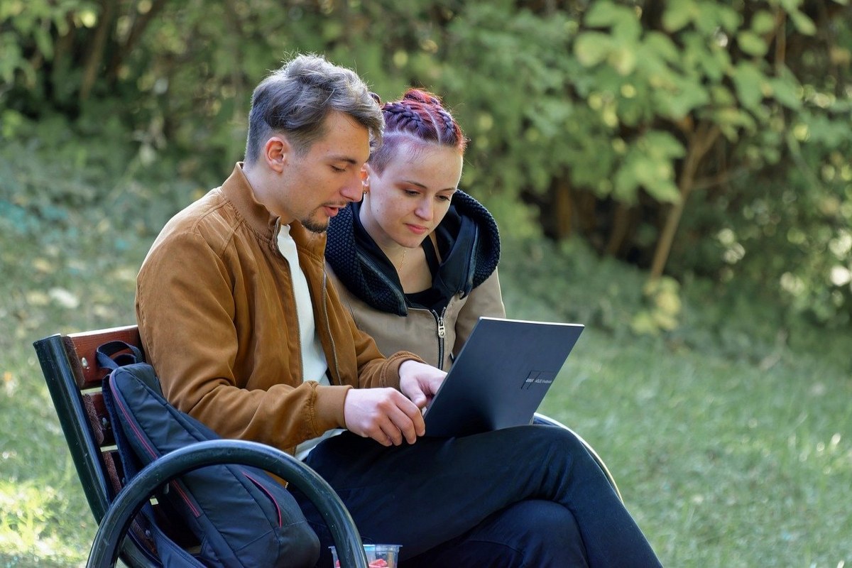 A man and a woman viewing a site on a laptop.