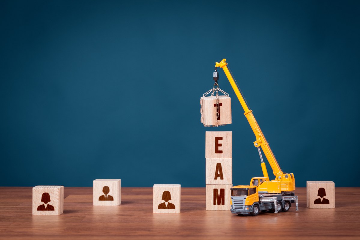 A toy crane arranges wooden blocks spelling 