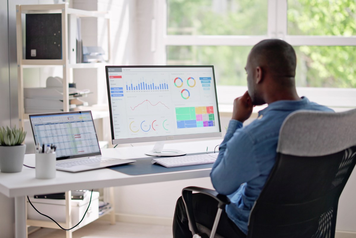 Behind view of businessman looking at analytics Dashboard on Computer.