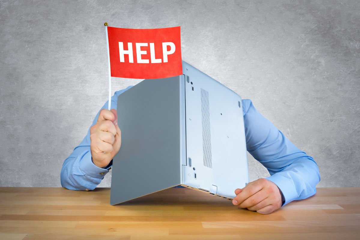 Businessman covers entired hear with laptop whilke waving flag saying Help.