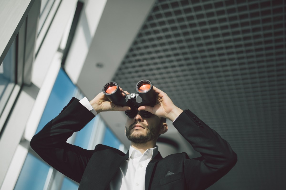 Businessman with binoculars spying on competitors.