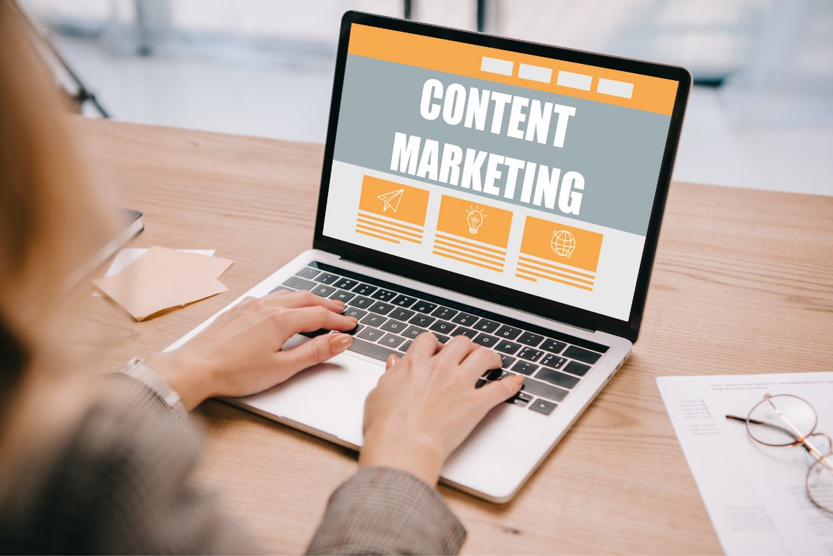Businesswoman typing on laptop with content marketing writing on screen.