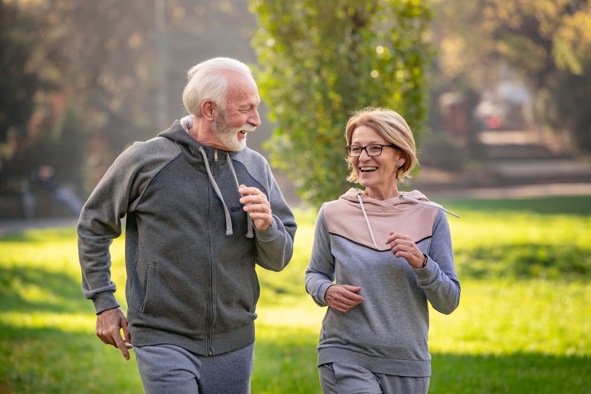 Cheerful active senior couple jogging in the park.