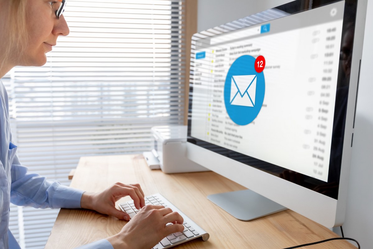 Email Marketing concept: woman facing desktop computer with email icon with notification.