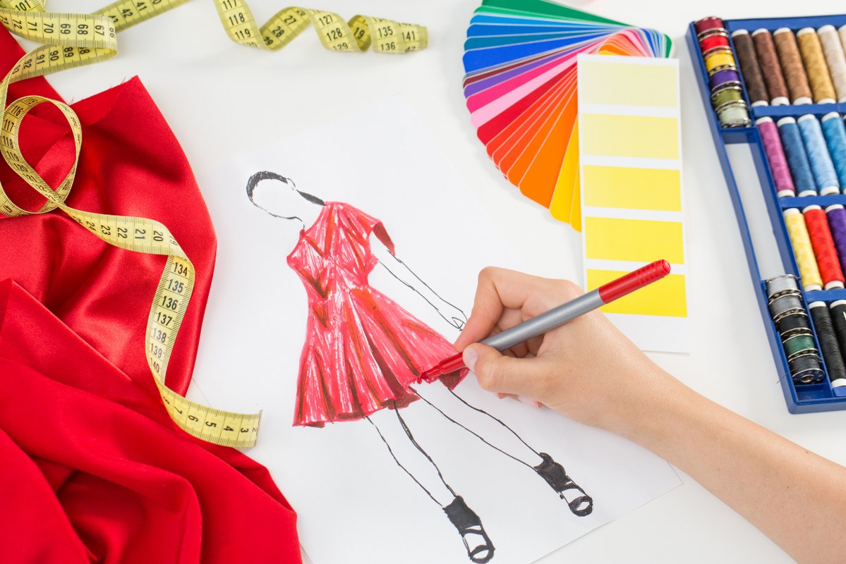 Fashion designer sketching a dress using red colored pen.