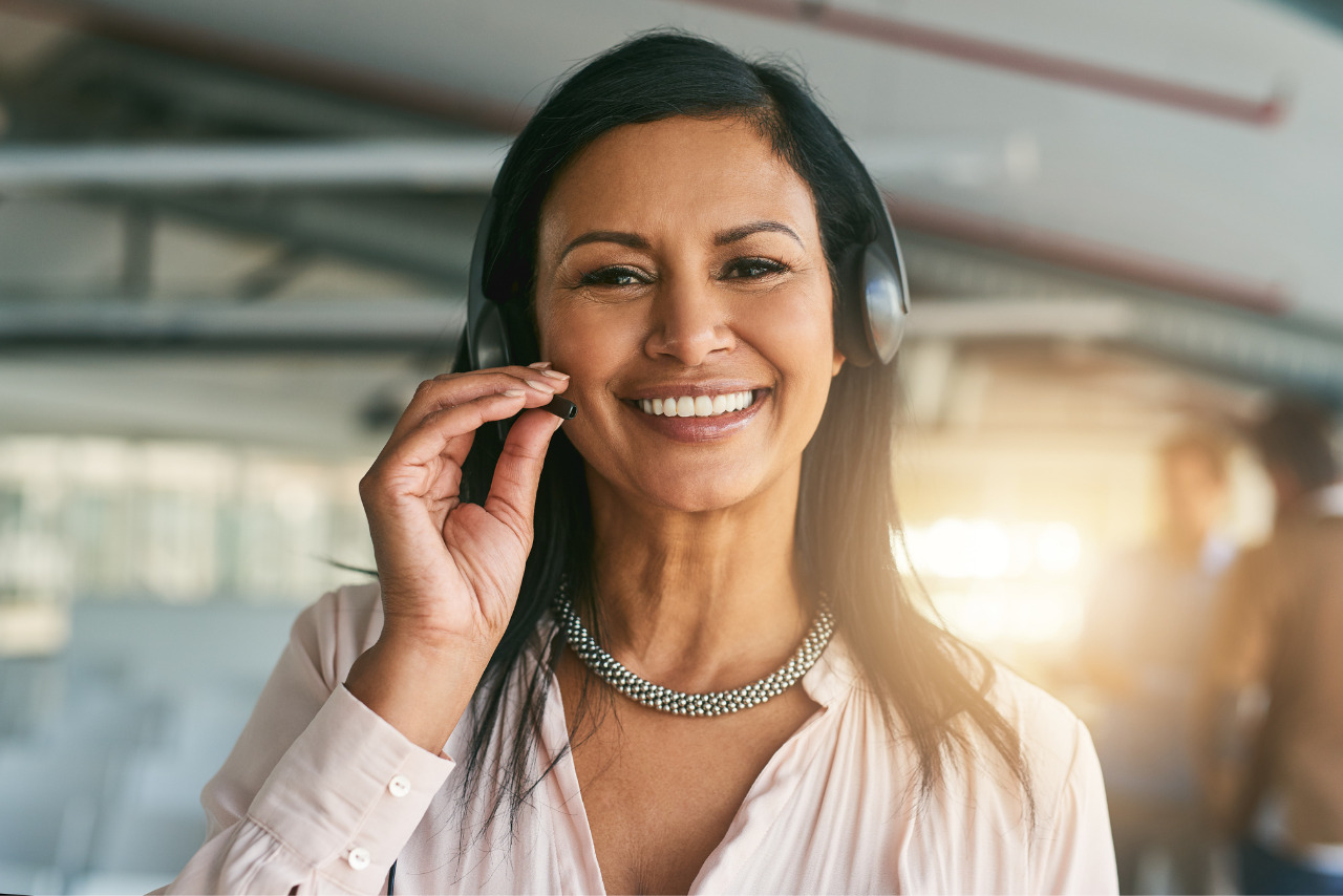 Female customer support person smiles while wearing headpiece.