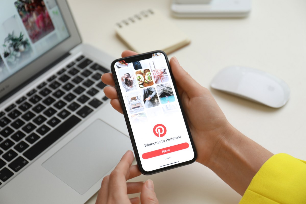 Female hands opening Pinterest app on smartphone.