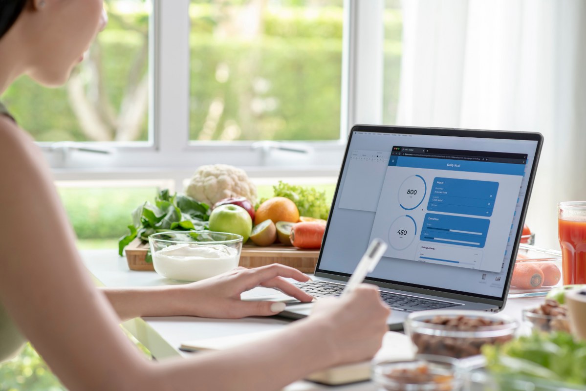 Female nutrition coach checking data from laptop with veggies around.