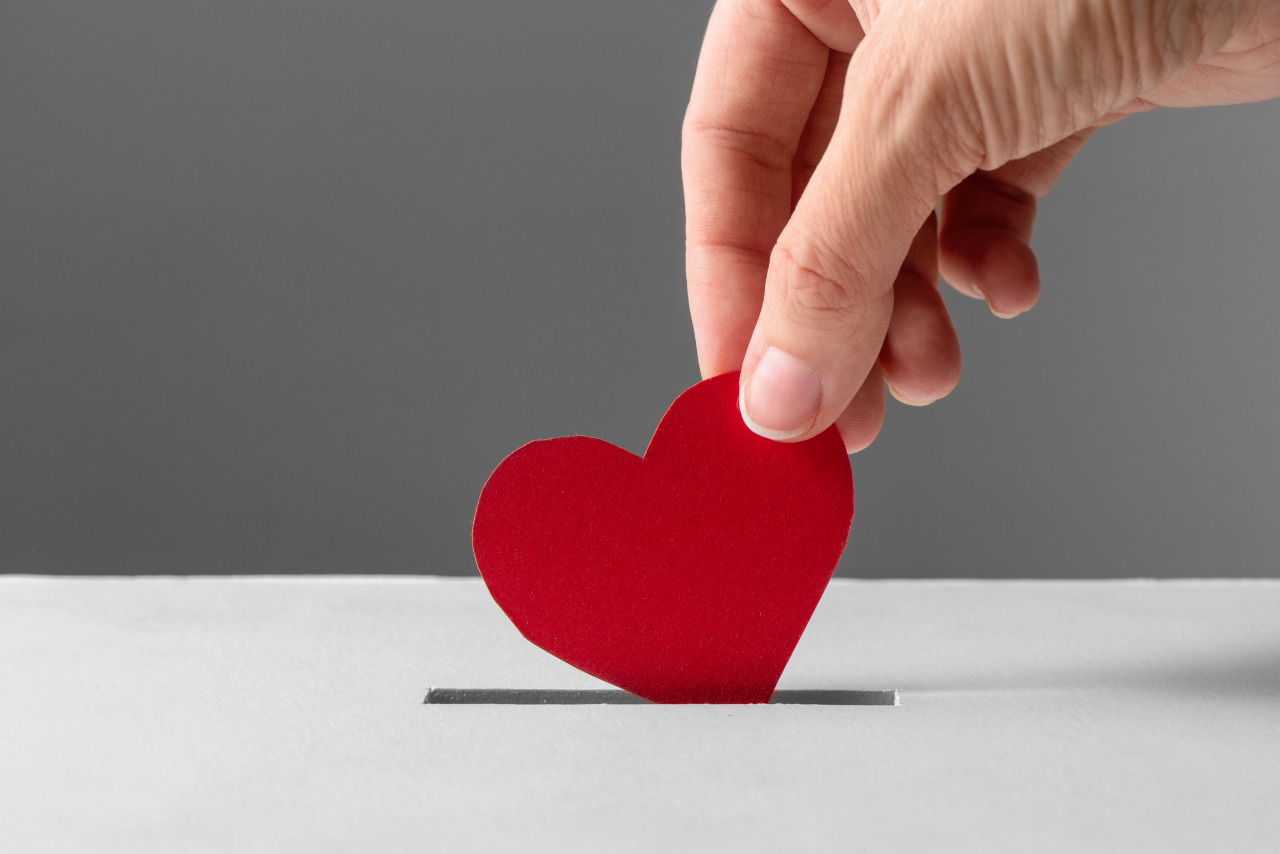 Hand Putting Red Heart into Donation Box.