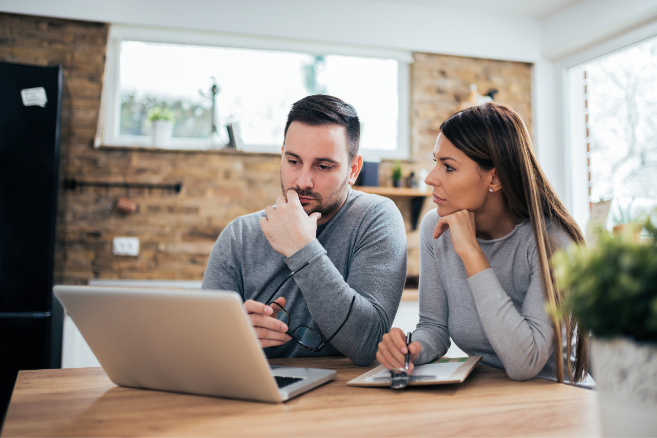 Husband and wife discusses finances using laptop.