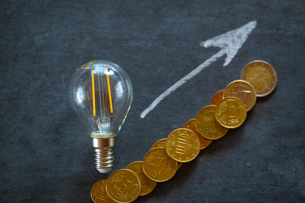Lightbulb, coins and arrow going up arranged on chalkboard.