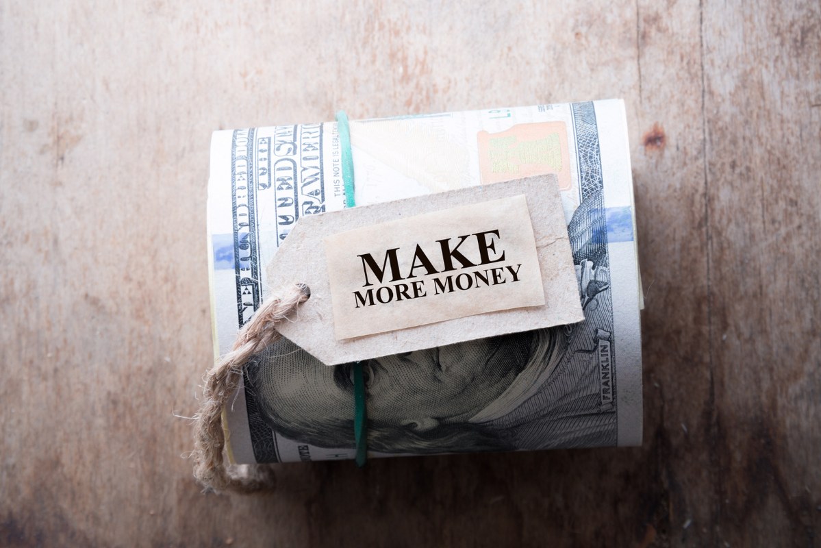 Make more money incription on wooden table with hundred dollar bills.