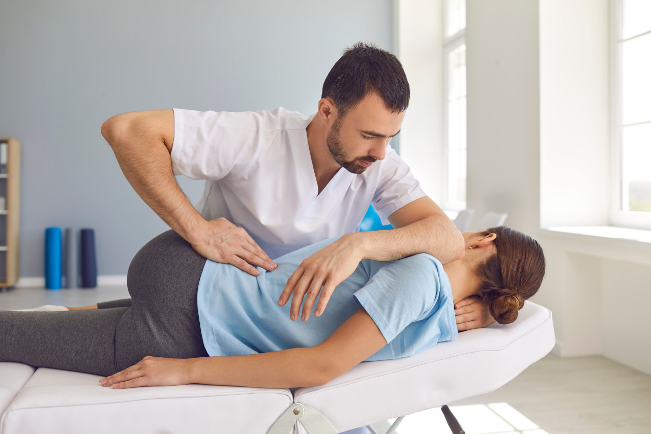Male chripractor fixing lying Womans back in manual therapy clinic.
