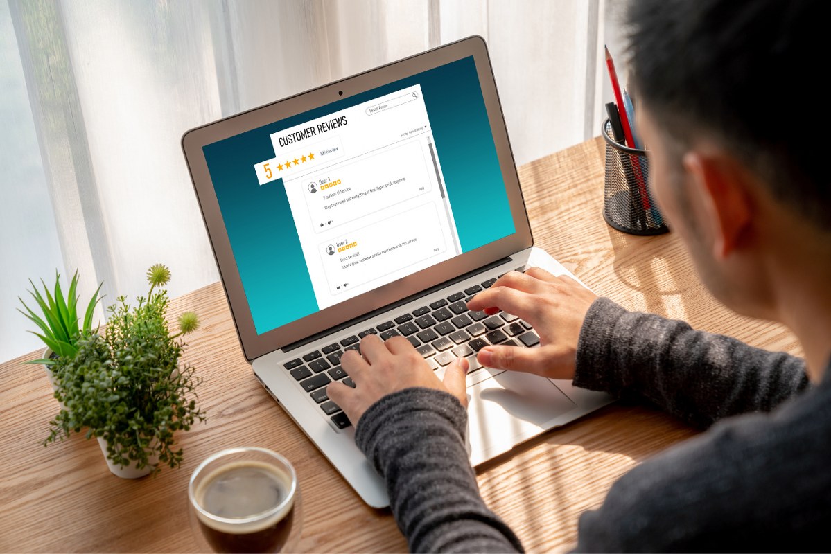 Male customer gives five star review using laptop.