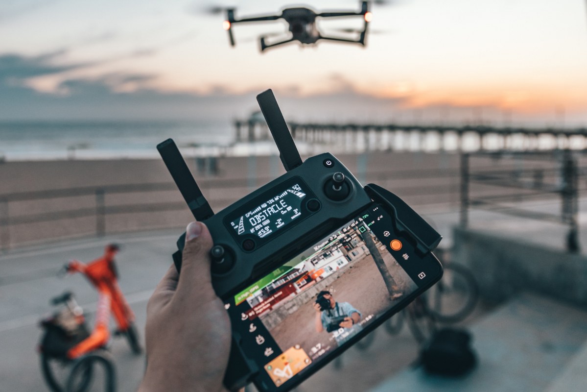 Male person holding controller and flying drone near him.