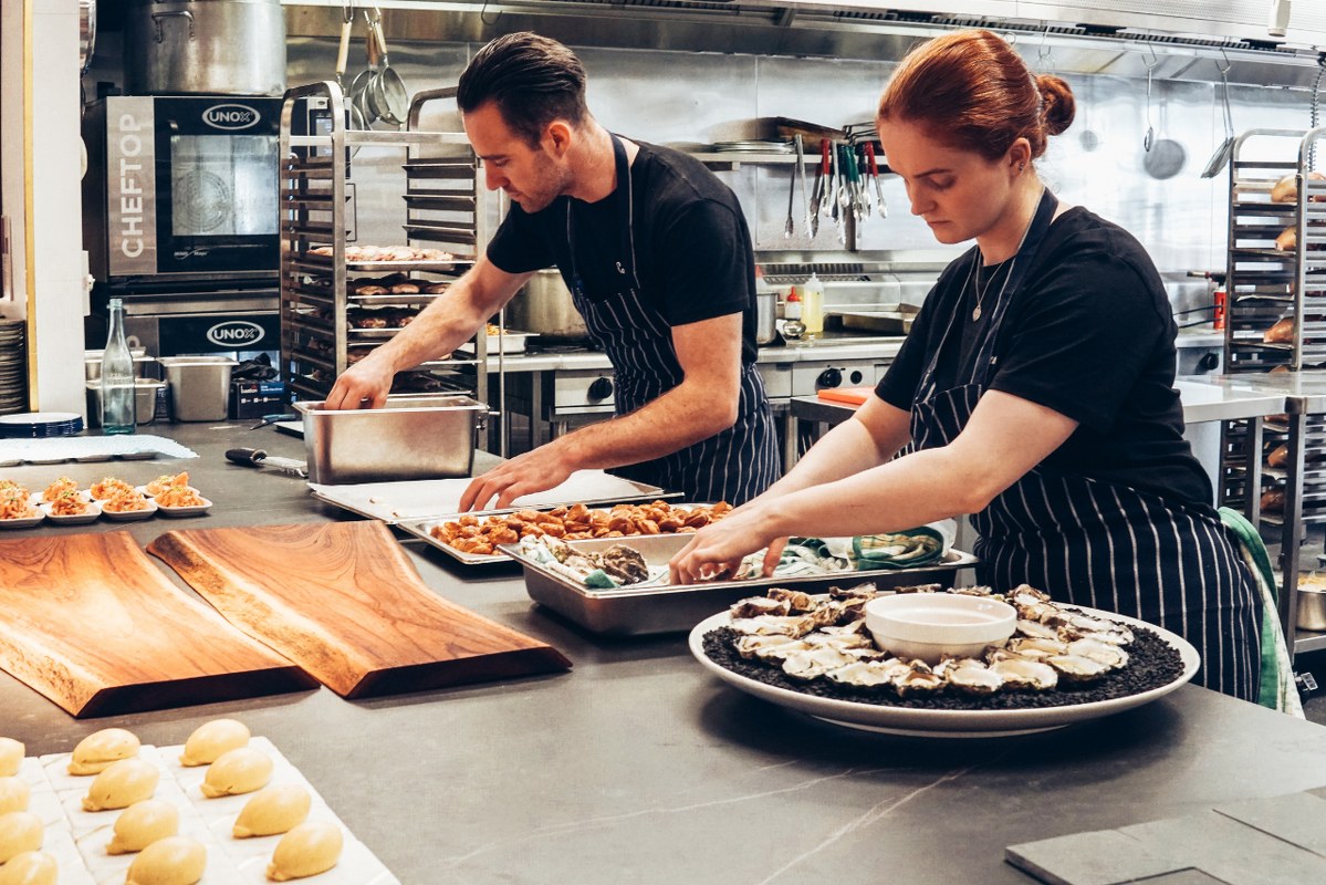 Man and Woman Wearing Black and White Striped Aprons Cooking.