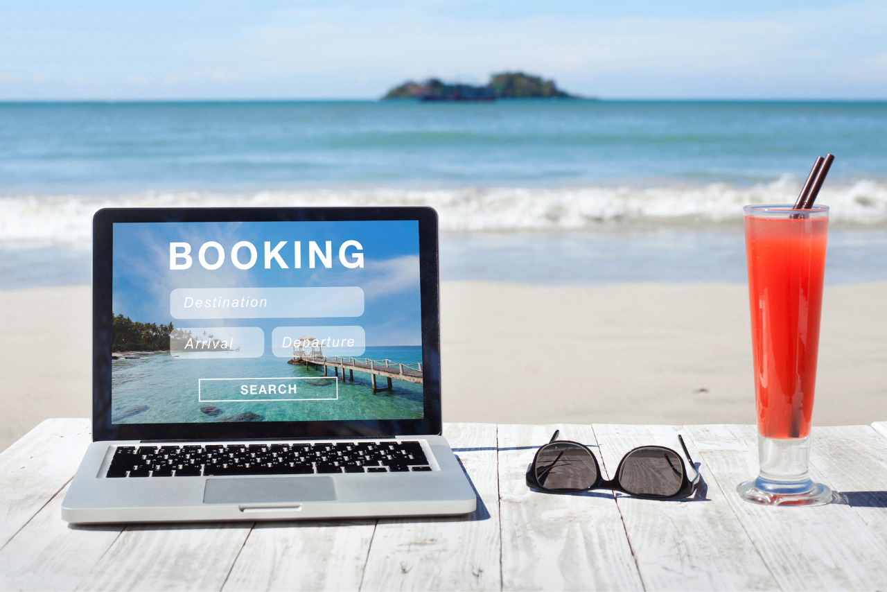 Open laptop displaying a flight booking page, next to sunglasses and a glass.