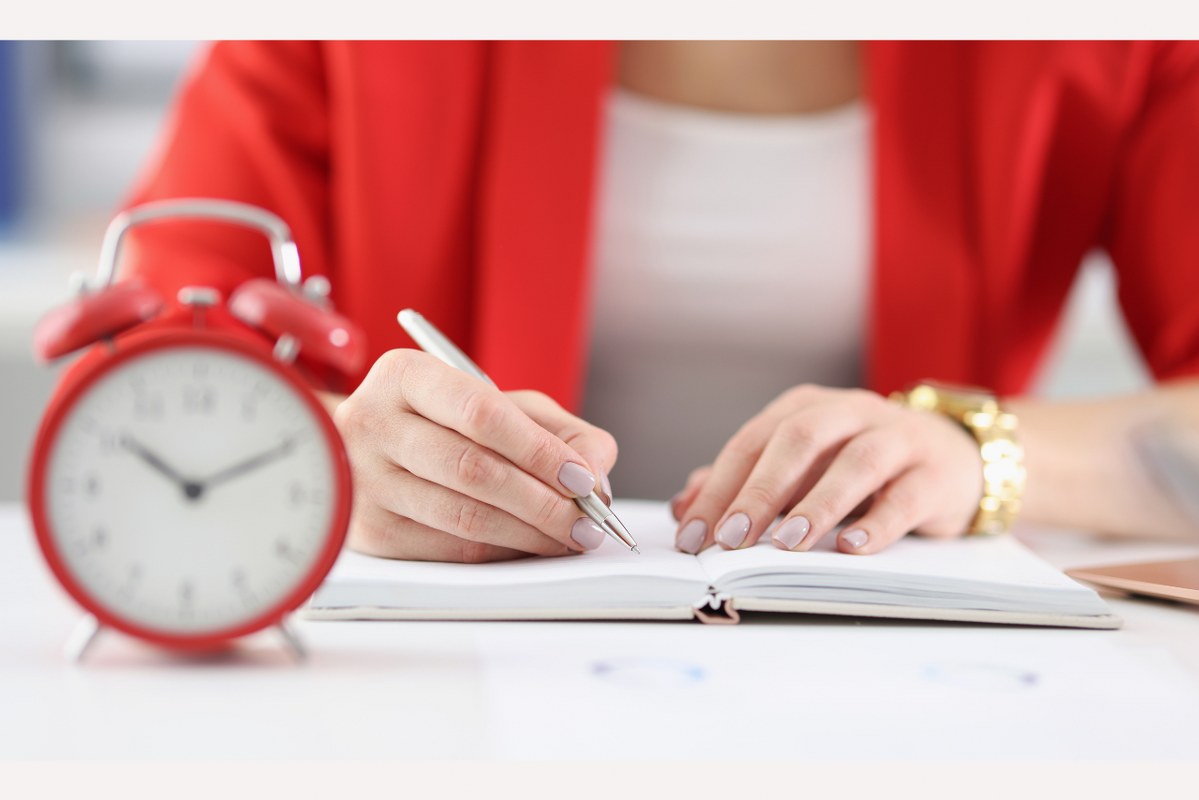 Student takes down notes with alarm clock on desk.